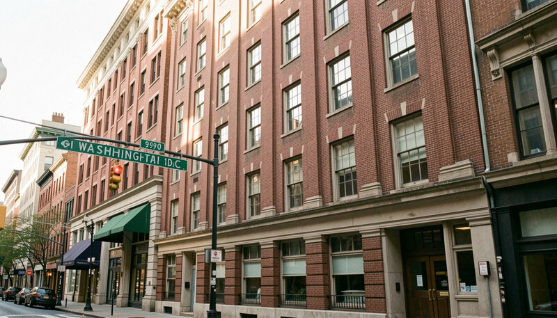 An archival-style view of a 1990s downtown Washington DC office block with brick facades and a street sign in soft light.